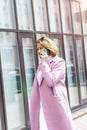 A woman with short brown hair walks around the city and talks on the phone in the spring. vertical photo.fashion style trend,