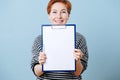 Woman with short ginger handing clipboard with paper to sign