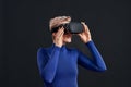 Woman with short hair in blue turtleneck wearing virtual reality headset, vr glasses isolated over dark background Royalty Free Stock Photo