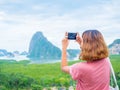 Woman with short hair using smart phone take a photo seascape view