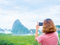 Woman with short hair using smart phone take a photo seascape view