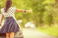 Woman in short skirt hitchhikes approaching car standing next to her broken down vintage vehicle Royalty Free Stock Photo
