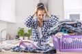 Woman shouts from anger and holds her head as she is frustrated from house chores and the pile of clothes she needs to iron Royalty Free Stock Photo