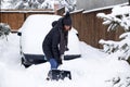 woman with shovel cleaning snow aeound car. Winter shoveling. Removing snow after blizzard