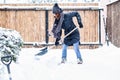 woman with shovel cleaning snow around car. Winter shoveling. Removing snow after blizzard