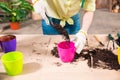 Woman with shovel, soil, flowerpots and plant on table