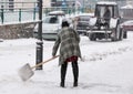 Woman shoveling winter snow in the city street