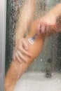 Woman in the shower shaves. Sexy young woman shaving her leg in shower cabin. Close-up view of female leg with razor. Girl hand