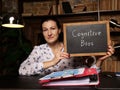 Woman showing black chalkboard with written text Cognitive Bias . Blurred background. Horizontal mockup