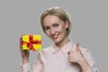 Woman showing gift box and thumb up. Royalty Free Stock Photo