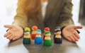 A woman showing a group of different colors wooden people toy in hands for diversity and business concept