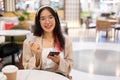 A woman is showing her credit card to the camera while sitting in a restaurant in a shopping mall Royalty Free Stock Photo