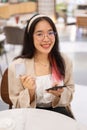 A woman is showing her credit card to the camera while sitting in a restaurant in a shopping mall Royalty Free Stock Photo