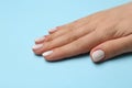 Woman showing her manicured hand with white nail polish on light blue background, closeup Royalty Free Stock Photo