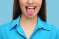 Woman showing her tongue on light blue background, closeup Royalty Free Stock Photo