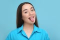 Happy woman showing her tongue on light blue background Royalty Free Stock Photo