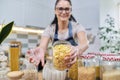 Woman showing a jar of corn flakes, food storage in the kitchen. Royalty Free Stock Photo