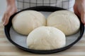 Woman showing three homemade loaves of bread in baking tray ready to be baked