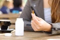 Woman showing vitamin pill on a coffee shop terrace Royalty Free Stock Photo