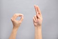 Woman showing word okay on grey background. Sign language