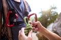 A woman shows a child how to use a carabiner for belaying