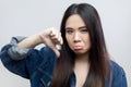 Woman shows disapproval sign, keeps thumb down, expresses dislike, frowns face in discontent. Royalty Free Stock Photo