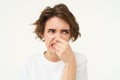 Woman shows dislike, shuts her nose from reeking bad smell, something stinks, stands over white background