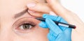 woman shows drooping eyelid for plastic surgery. Doctor plastic surgeon marks with a felt-tip pen a marker for a Royalty Free Stock Photo