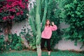 A woman shows her teeth from behind a large cactus