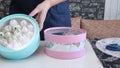 A woman shows a homemade marshmallow packed in pink and turquoise boxes.