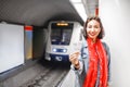 Woman shows two tickets at the background of the approaching train in the subway. Concept of urban public underground