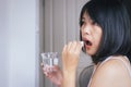 Woman sick with pill putting in her mouth,female taking medicines and a glass of water Royalty Free Stock Photo