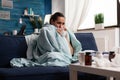 Woman with sickness wrapped in blanket at home ill