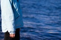 Woman side view in a jacket on a background of blue water. Copy space. Melancholy mood