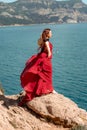 A woman, a side view in a red flying dress fluttering in the wind, a girl in a fluttering dress on the background of the Royalty Free Stock Photo