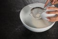 Woman sieving flour into the bowl