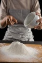 Woman sieving flour from the bowl on the wooden board