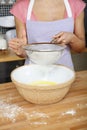Woman sieving flour into mixing bowl. Conceptual image