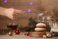 Woman sieving icing sugar on cookies at wooden table, closeup