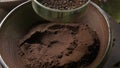 A woman sifts the chopped roasted coffee through a sieve.