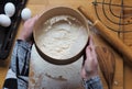 A woman sifts flour in a sieve on a kitchen cutting Board.Home cooking