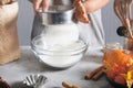 Woman sifts flour using sieve into glass bowl