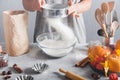 Woman sifts flour using sieve into glass bowl