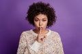 Woman with sign silence put lips on finger on purple wall