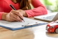 Woman signing car insurance document or lease paper. Person buying or selling new or used car. Writing signature on Royalty Free Stock Photo