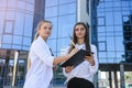 Woman signing contract on clipboard. They are in business suits and standing outside office Royalty Free Stock Photo