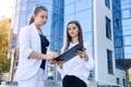 Woman signing contract on clipboard. They are in business suits and standing outside office Royalty Free Stock Photo