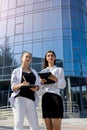 Woman signing contract on clipboard. They are in business suits and standing outside office Royalty Free Stock Photo