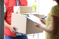 Woman signing for delivered parcels on doorstep. Courier service Royalty Free Stock Photo