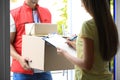 Woman signing for delivered parcels on doorstep. Courier service Royalty Free Stock Photo